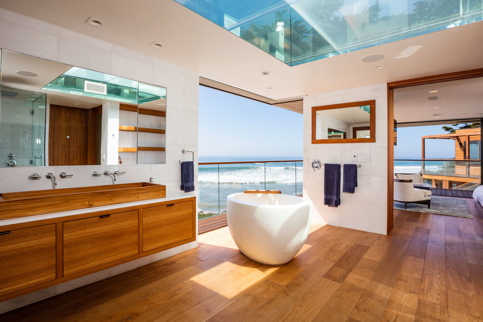 Bright oceanfront bathroom with warm teak flooring and teak vanity