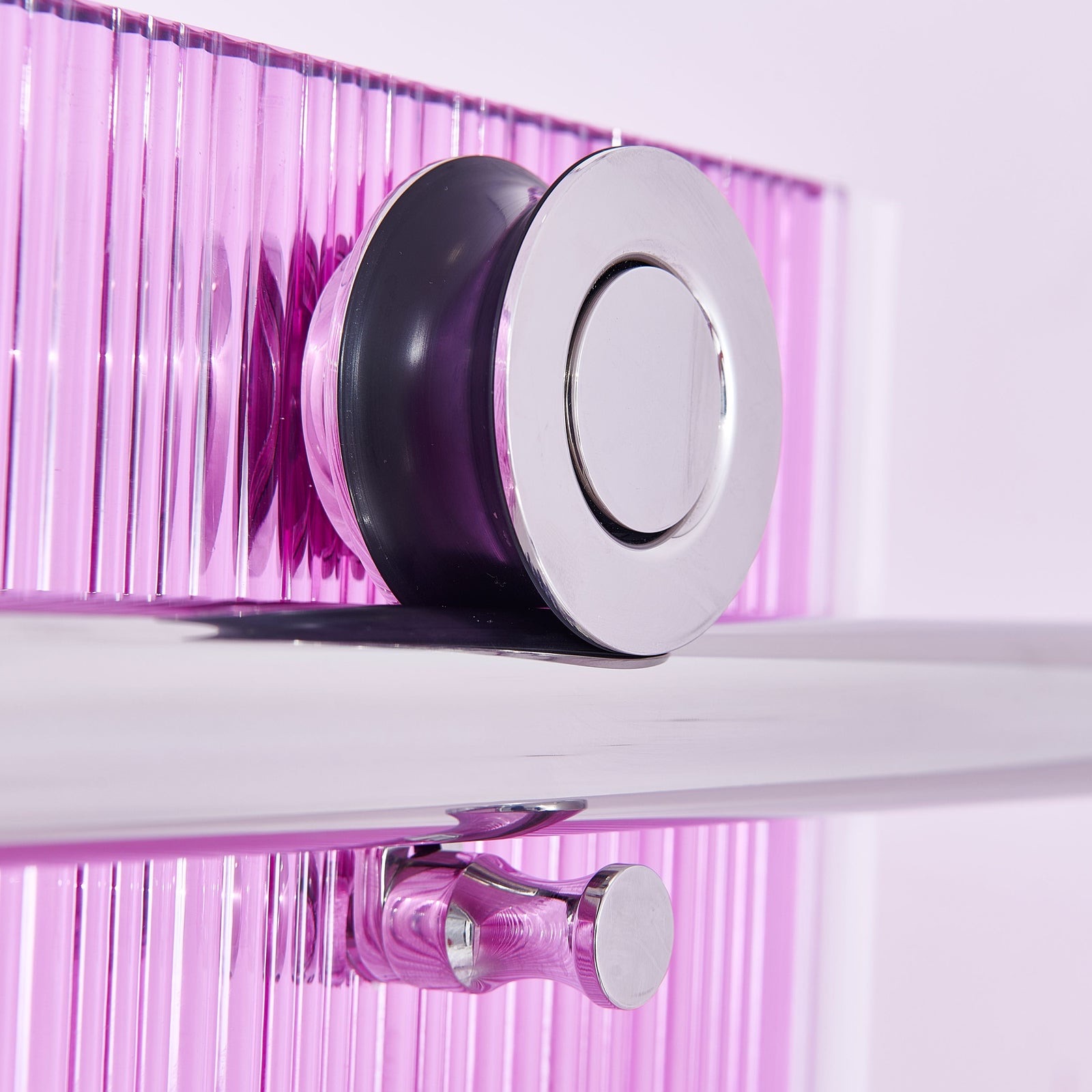 Close-up of pink ribbed glass and polished chrome shower hardware